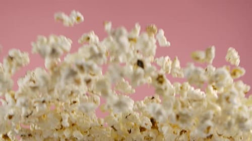 Superzeitlupenaufnahme von Popcorn auf rosafarbenem Hintergrund nach der Explosion
