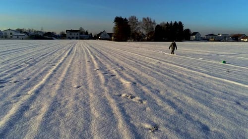 Little boy playing with a ball in field full of snow