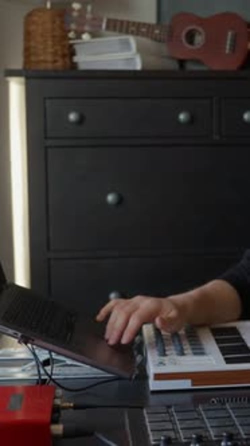 Man Creating Music with Keyboard and Laptop