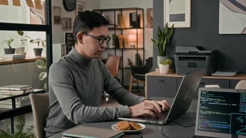 Porträt eines lächelnden Webentwicklers, der auf einem Laptop im Büro eines IT-Unternehmens programmiert