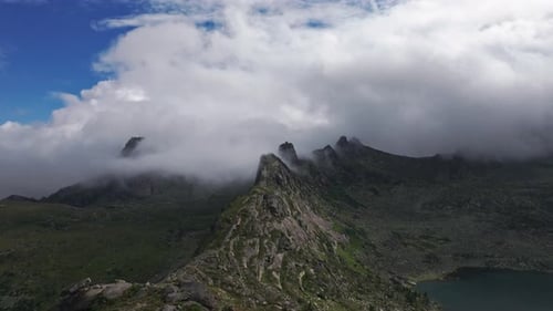 Clouds Embracing Majestic Mountain Peaks and Serene Lake