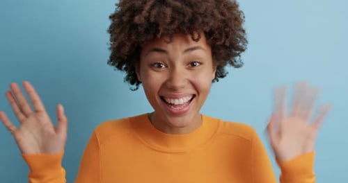 Happy young woman waving her hands cheerfully