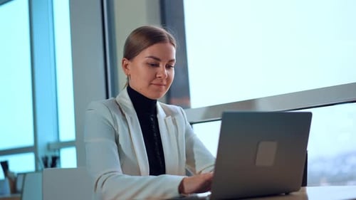 Woman Typing on Laptop in Modern Office