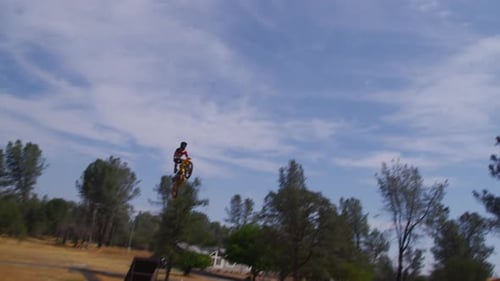 Teen Jumps Motorcycle on Ramp in Rural Setting