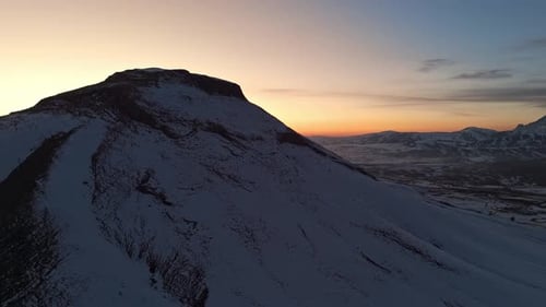 A mountain range covered in snow at sunset time