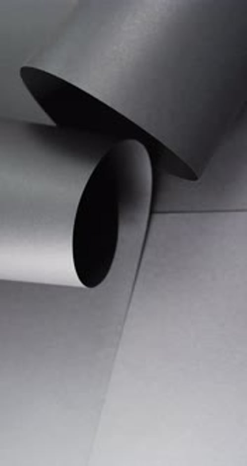 Vertical video of close up of rolled up black paper and copy space on black background
