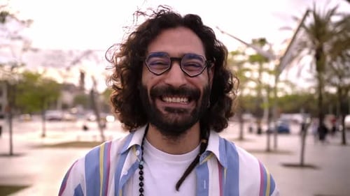 Retrato de um homem italiano bonito olhando para a câmera sorrindo em pé ao ar livre em um dia ensolarado
