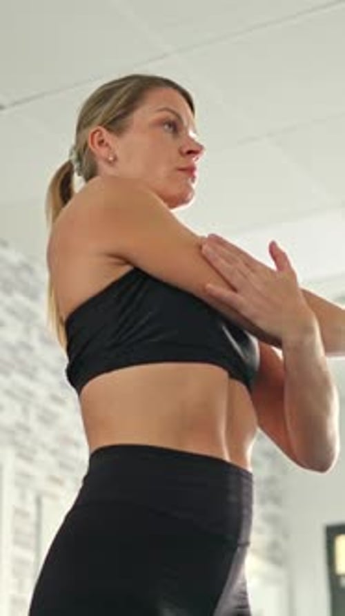 Athletic Woman Stretching Arm in Gym Setting