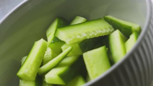 Concombres biologiques frais coupés dans un bol alors que la caméra se déplace lentement