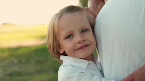 Portrait d'un enfant serrant le ventre d'une mère enceinte