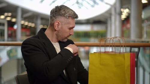 Man Examining a Ten Dollar Bill After Shopping in a Retail Area