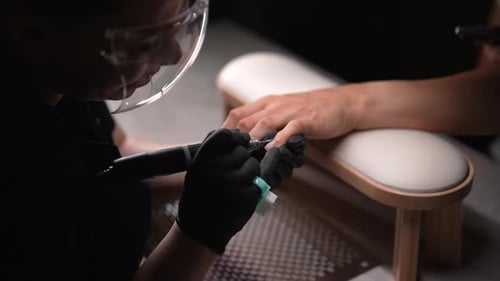 Top View of Female Manicurist Wearing Protective Face Shield Using Electric Nail Drill to Perform