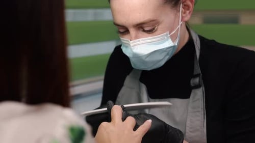 Manicurist Filing Client's Nails at Salon