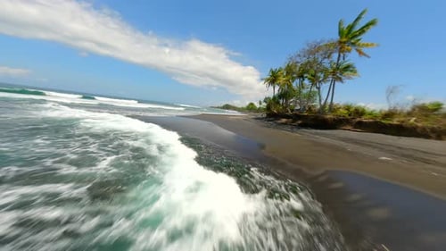 FPV Flight Over Black Sand Beach with Ocean Waves and Palm Trees Bali Indonesia