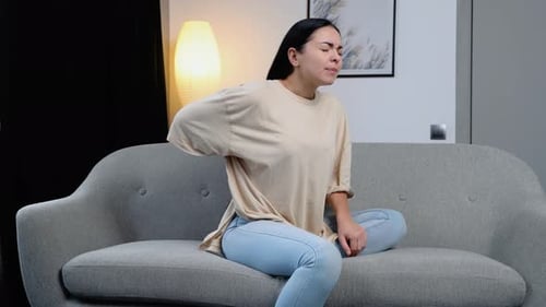 Woman Experiencing Lower Back Pain on Sofa