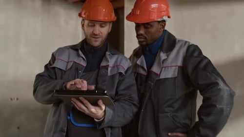Two Construction Engineers Discussing Plans on Tablet at Worksite