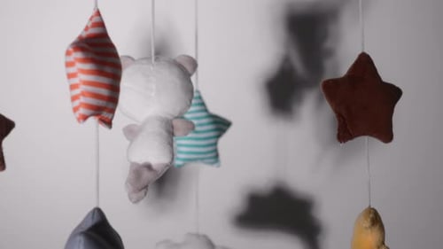 Woven Toys Hanging On Crib Mobile With Lullaby Music Inside A Nursery Room. - close up