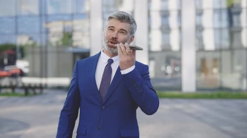 Caucasian Office Manager is Standing By the Business Center Utilizing Their Phone to Record a Voice