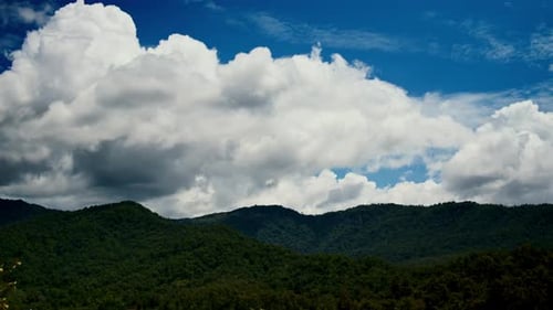 Timelapse of the Big White Clouds Moving in the Blue Sky Above the Green Hills