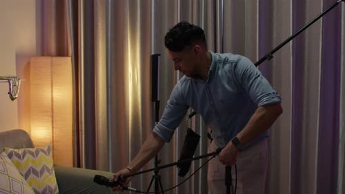 Man adjusting podcast equipment and microphone at home in a creative indoor setup