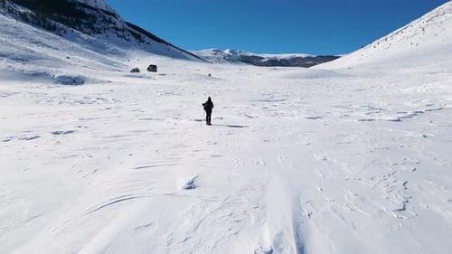 Aerial drone view of solo hiker walking in the mountains during the winter.
