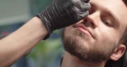 Man Getting Eyebrows and Beard Groomed at Barbershop