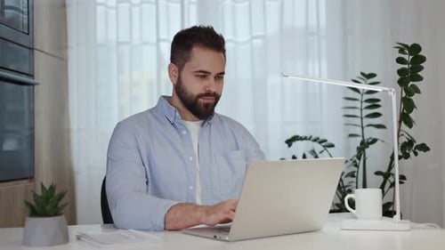 Positive Male Freelancer Typing Business Plan on Modern Laptop in Home Office