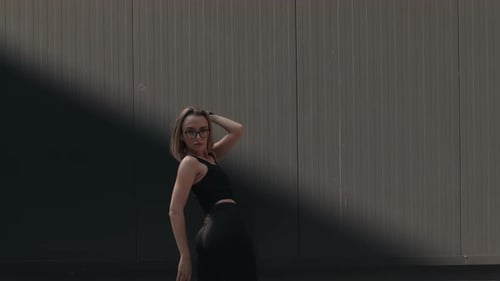 Woman Dancing Against a Gray Urban Wall