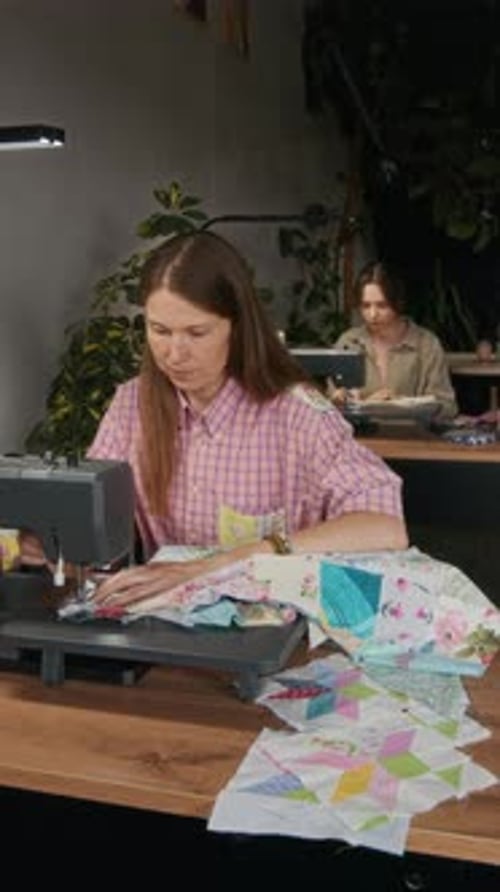 Two Caucasian Female Tailors Sewing Garments on Machines in Workshop
