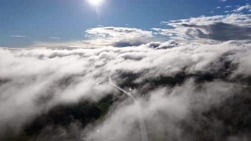 Serene aerial landscape of clouds and sun with a road below, Canada