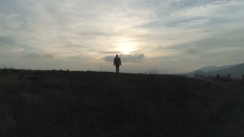 Man Walking Toward Lake at Sunrise on Hill