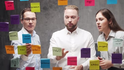 Team of Business People is Doing Brainstorm at a Meeting Using Stickers on the Glass Office Workers