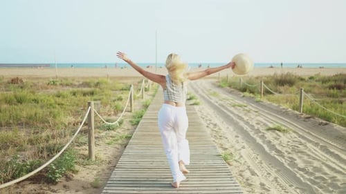 Rückansicht einer Touristin mit Hut, die glücklich rennt und ihren Sommerurlaub genießt