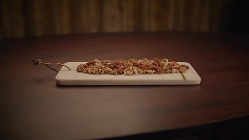 Hand Picks Nut From Assortment on Marble Tray