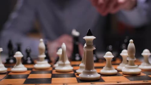 Hand Takes White Queen in Chess Game