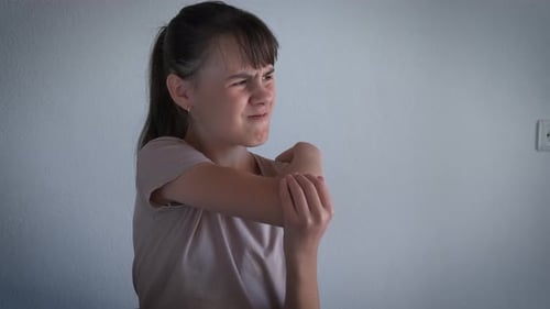 Young Woman Rubbing Sore Elbow in Home