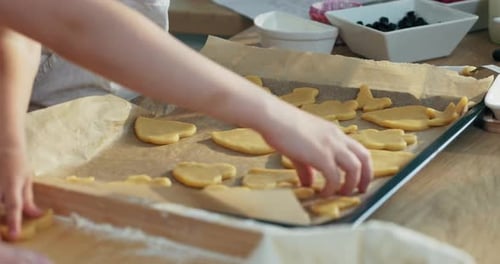 Nahaufnahme Schuss Kinderhände, die hausgemachte Kekse und Kekse auf ein Backblech legen, um sie neu modern zu machen