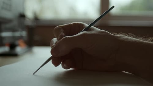 Nahaufnahme eines männlichen Handmalers vor einem Fenster rot auf weißes Papier