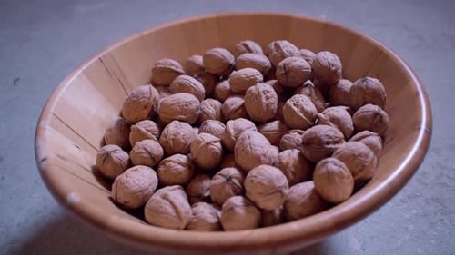 Dried walnuts in a wooden bowl. Adding some fresh walnuts to the bowl.