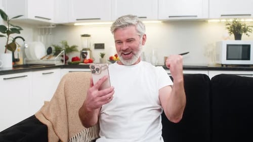 Man Sits on Couch and Reacts to Phone