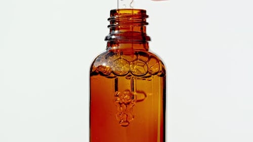Brown Bottle Being Filled with Amber Liquid