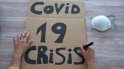 Writing COVID-19 Crisis Sign on Cardboard with Mask