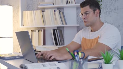 Young Adult Working on Laptop at Home Desk