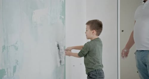 Boy Smoothing Wall with Plaster Indoors