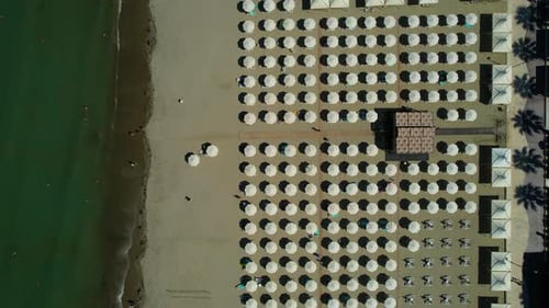 Background of beach umbrellas lined up in front of hotels and resorts on the sandy beach of Adriatic