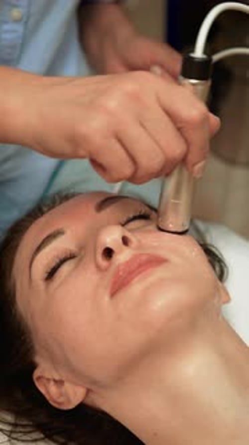 Woman Receiving Facial Cosmetic Treatment in Spa Clinic