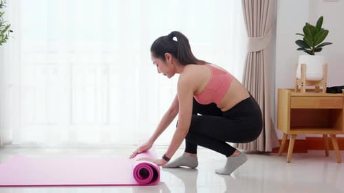 Young asian woman rolling with mat yoga on floor for preparation meditation and exercise.