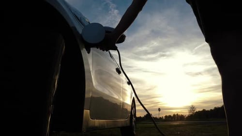 Unplugging Electric Car at Sunset in a Rural Area