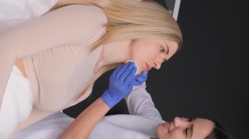 Cosmetologist Treating Patient's Lips with Cotton Pad