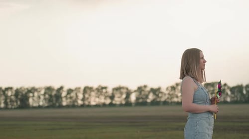 Young Woman Holding Pinwheel in Rural Field